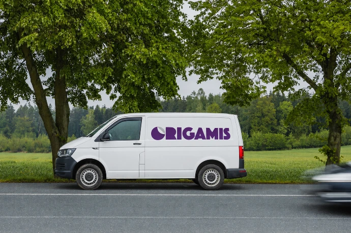 Bílá dodávka s logem Origamis stojící u silnice